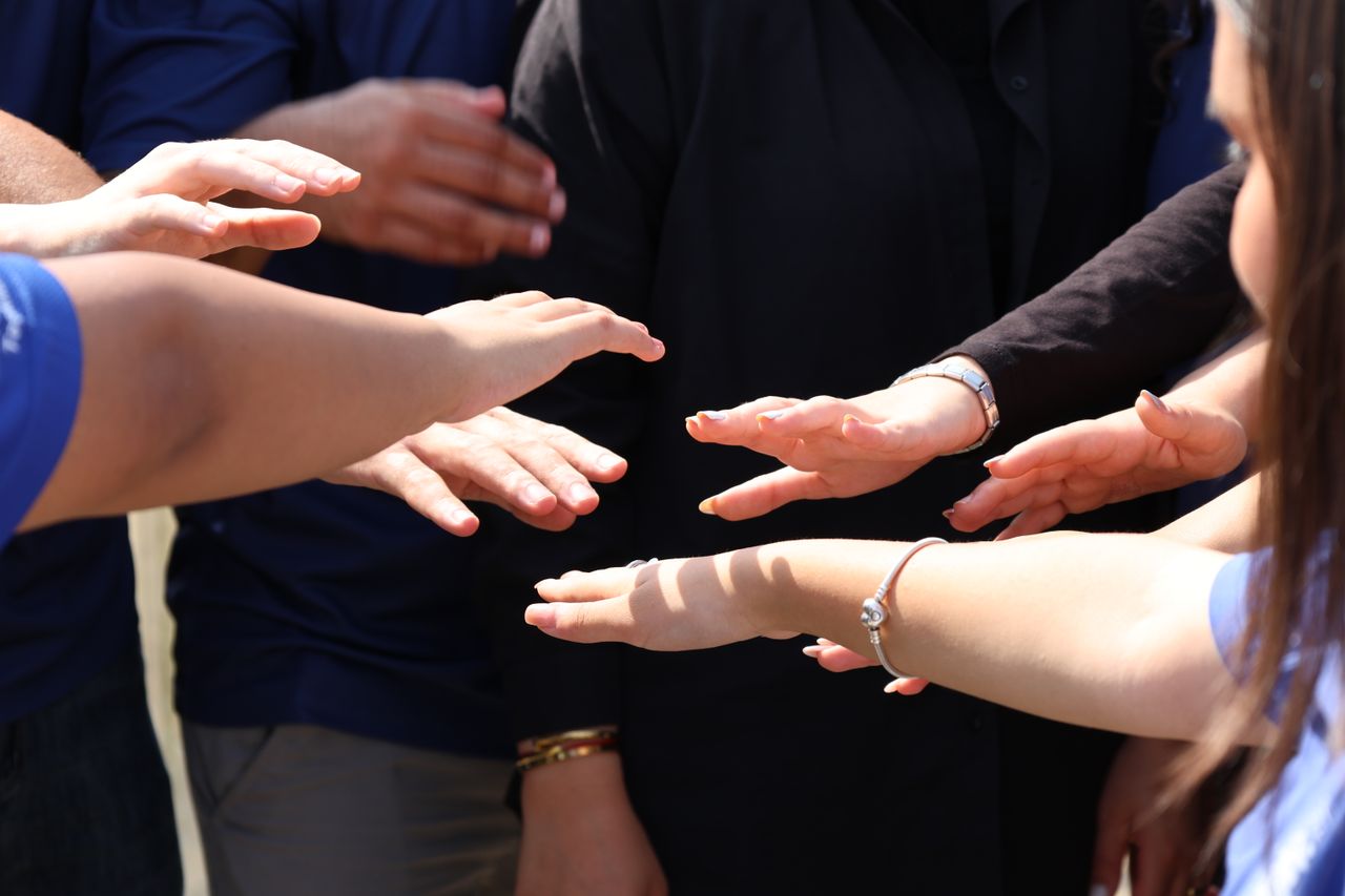 A diverse group of people placing hands together symbolizing teamwork and unity.